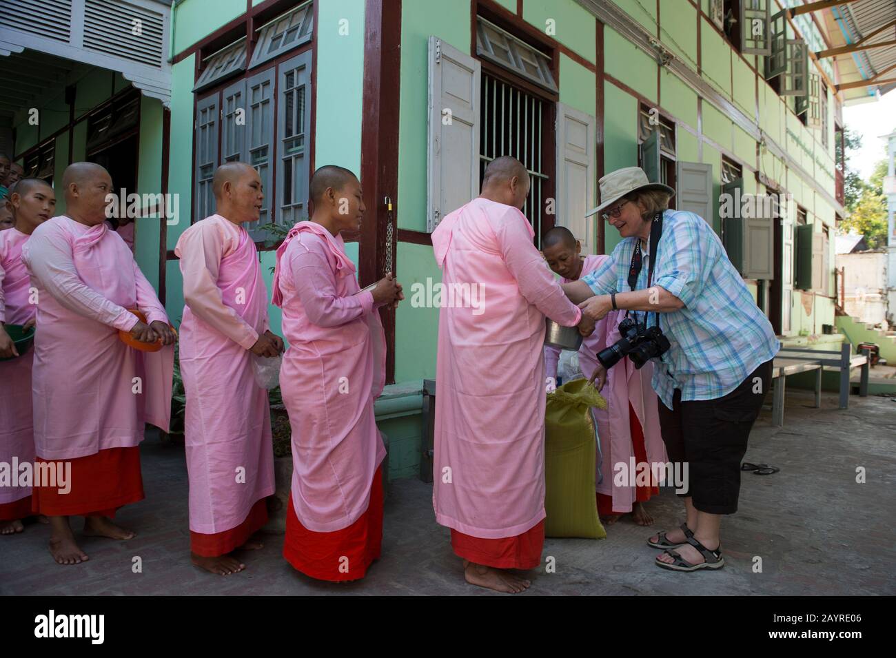 Tourisme donnant du riz à des religieuses alignées pour la cérémonie de remise des Alms à Zayertheingi, une nunnery bouddhiste à Sagaing, une ville en dehors de Mandalay, au Myanmar. Banque D'Images