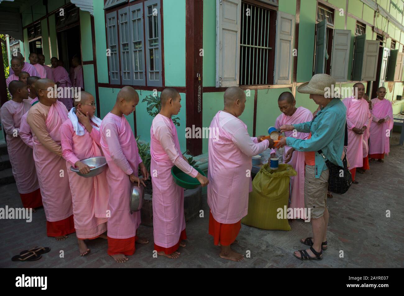 Tourisme donnant du riz à des religieuses alignées pour la cérémonie de remise des Alms à Zayertheingi, une nunnery bouddhiste à Sagaing, une ville en dehors de Mandalay, au Myanmar. Banque D'Images