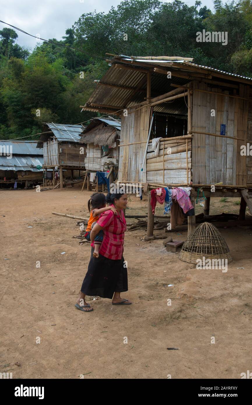 Une femme locale marche devant des maisons traditionnelles sur pilotis en bambou dans le village Ban Muangkeo, un village du patrimoine culturel du Mékong Banque D'Images