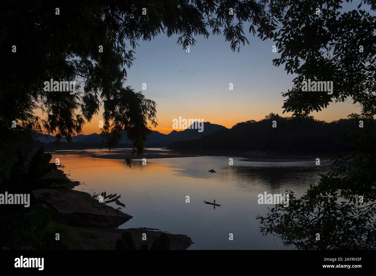 Vue sur le Mékong avec un pêcheur en bateau après le coucher du soleil près de la ville de Luang Prabang, classée au patrimoine mondial de l'UNESCO, au Laos central. Banque D'Images