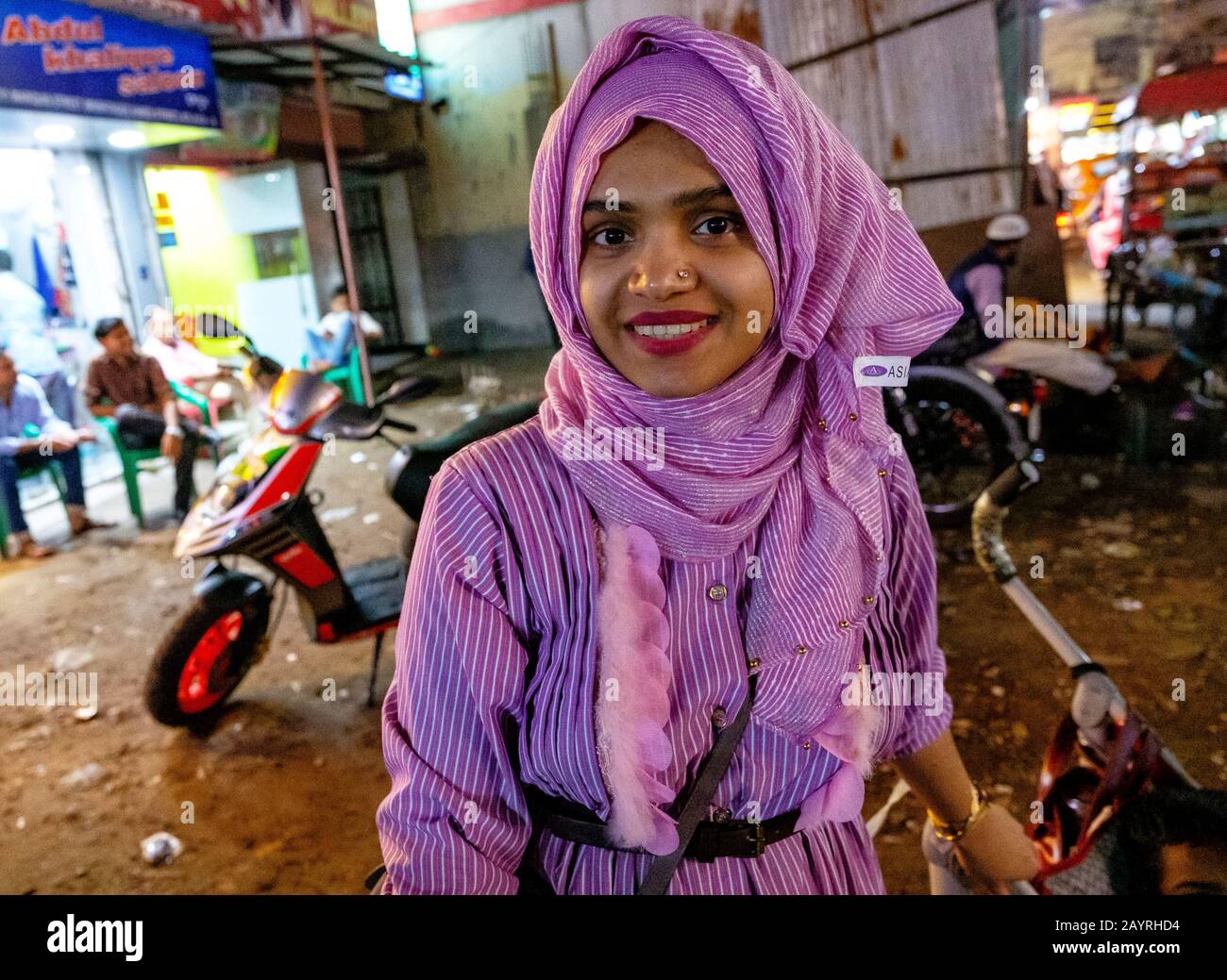 Une femme musulmane en violet penchant sur sa moto à Kolkata, en Inde Banque D'Images