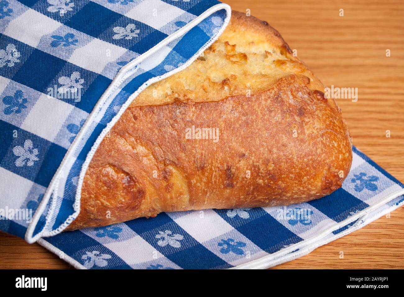 Pain de trois pains au fromage, partiellement emballé par une serviette en tissu bleu à damier Banque D'Images