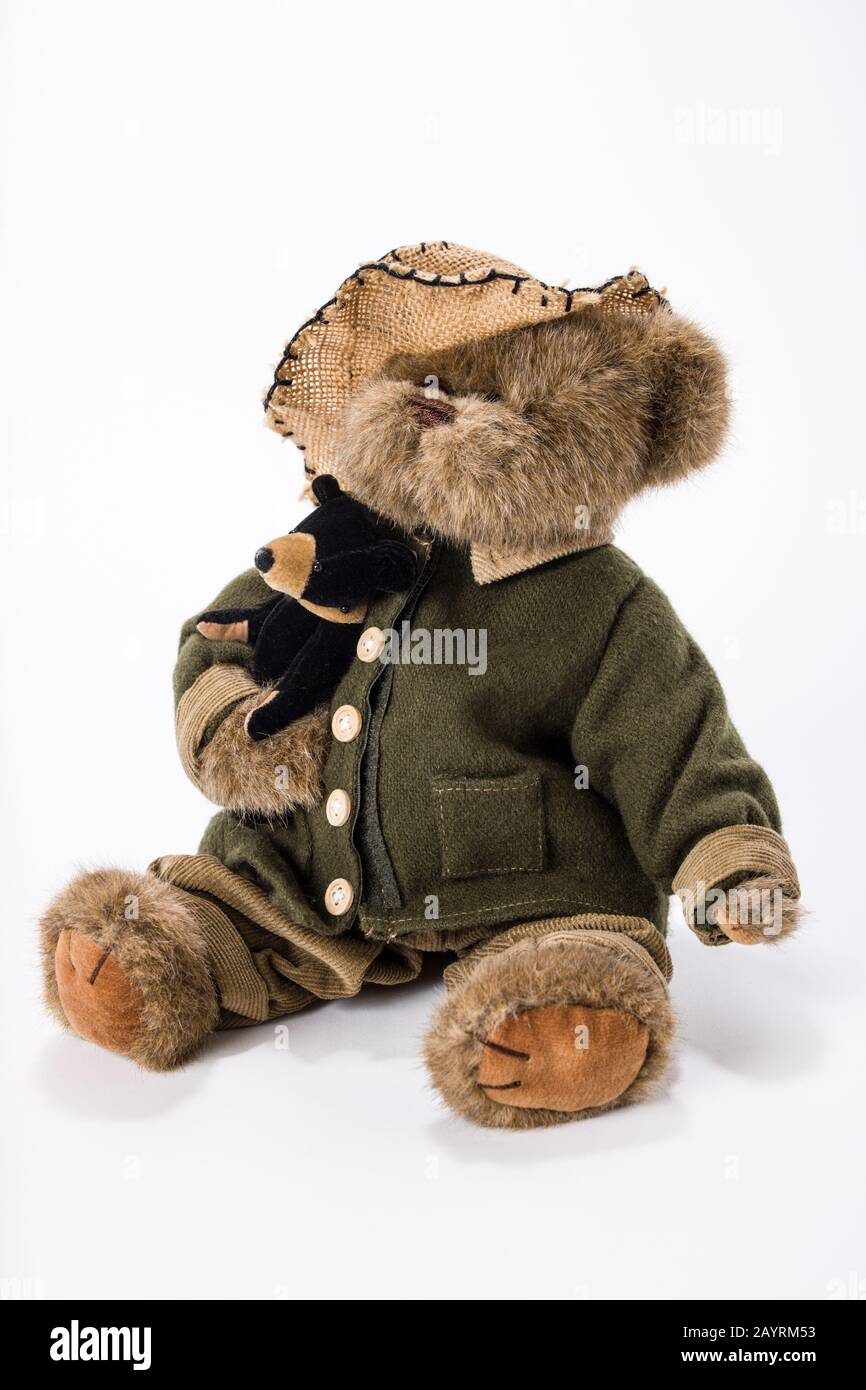 Ours en peluche portant une veste, un pantalon et un chapeau, tenant son propre ours en peluche Banque D'Images