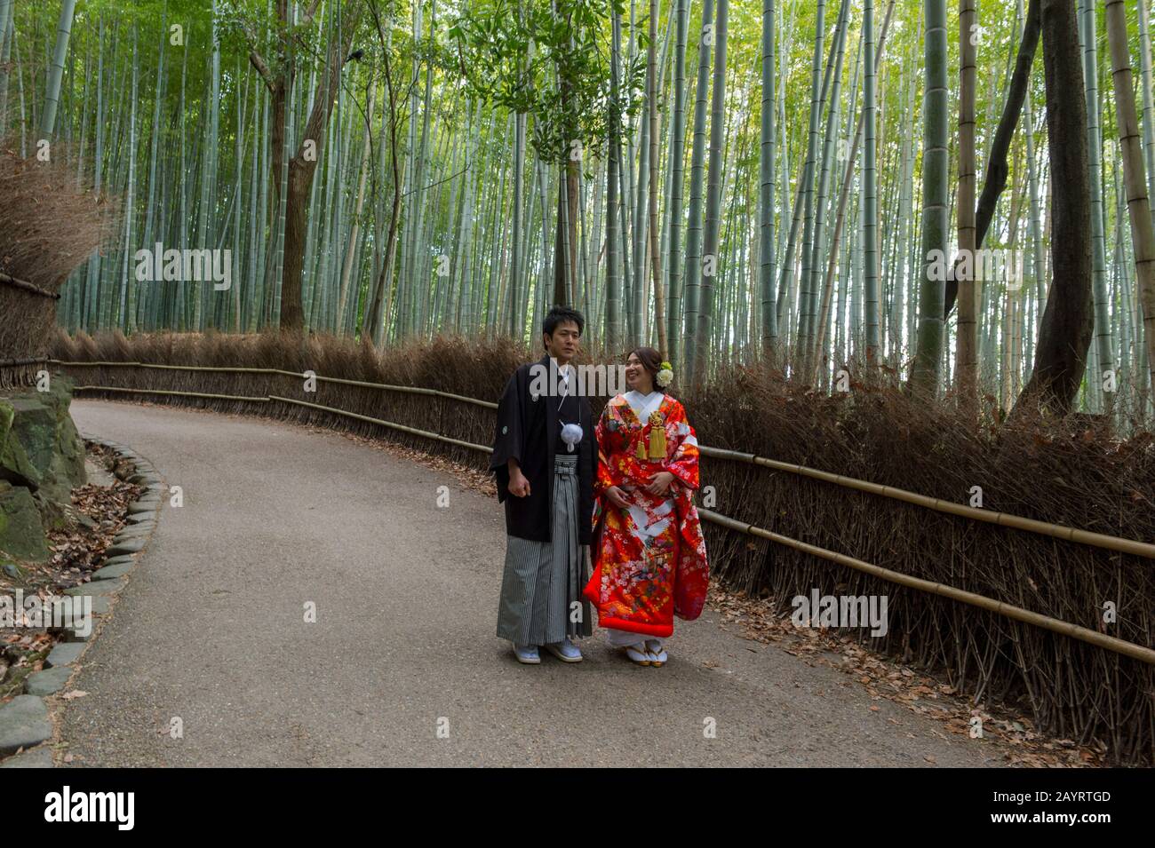 Une mariée japonaise et un marié sur le chemin à travers la bosquet de bambou (bambou Moso) au Temple Tenryu-ji (site du patrimoine mondial de l'UNESCO) à Arashiyama, Kyot Banque D'Images