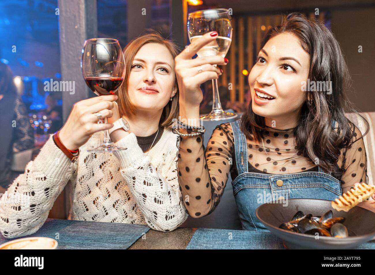 Deux filles amis s'amusent et bavarder tout en buvant un verre de vin dans un restaurant dans une discothèque. Le concept de détente et de frégate Banque D'Images