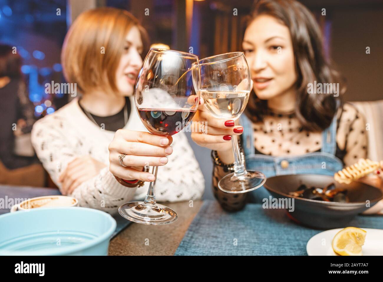 Deux filles amis s'amusent et bavarder tout en buvant un verre de vin dans un restaurant dans une discothèque. Le concept de détente et de frégate Banque D'Images