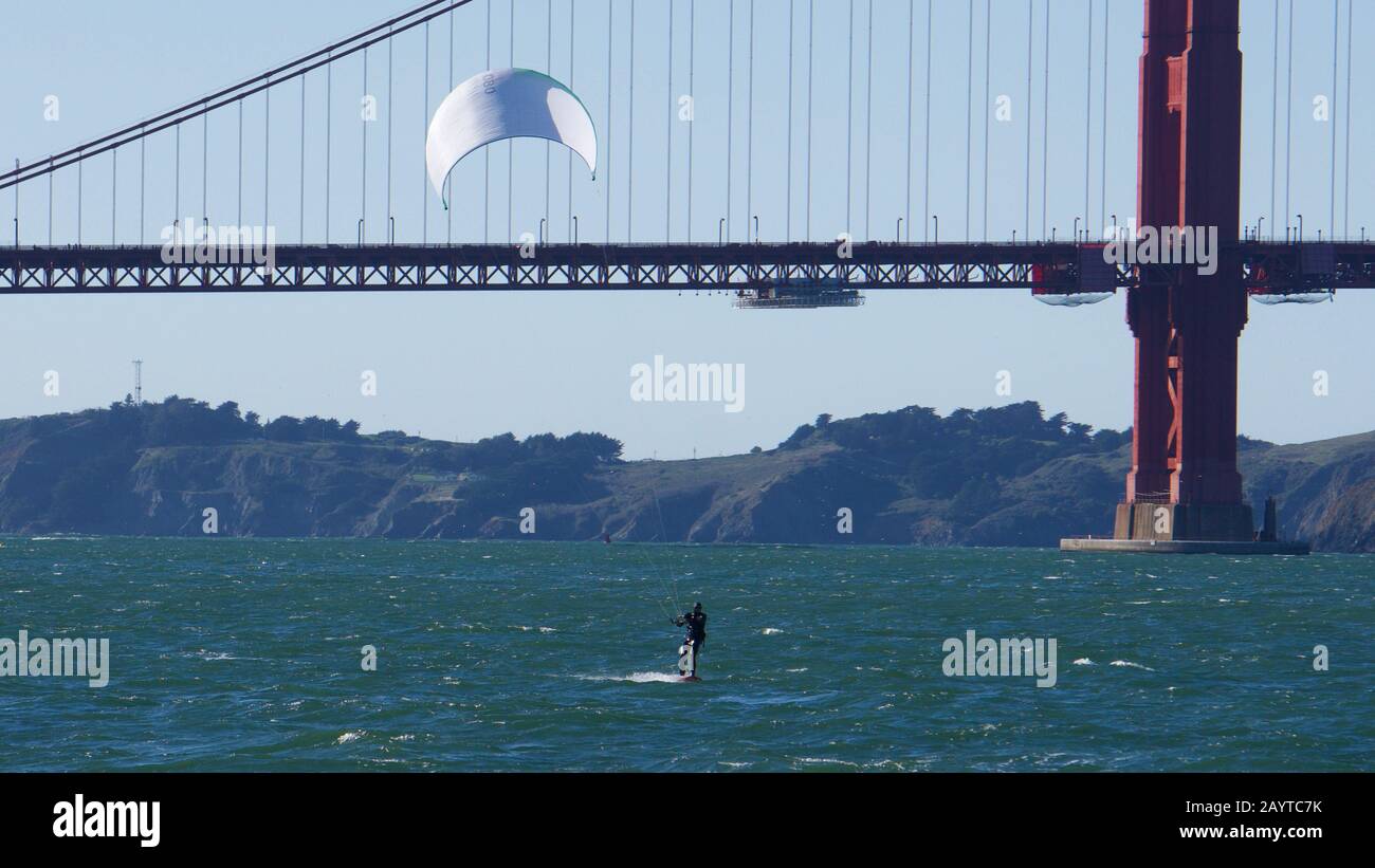 Kite surfeur ou kiteboarder avec voile blanc sur une journée venteuse devant le Pont du Golden Gate et les Marin Headlands, baie de San Francisco. Banque D'Images