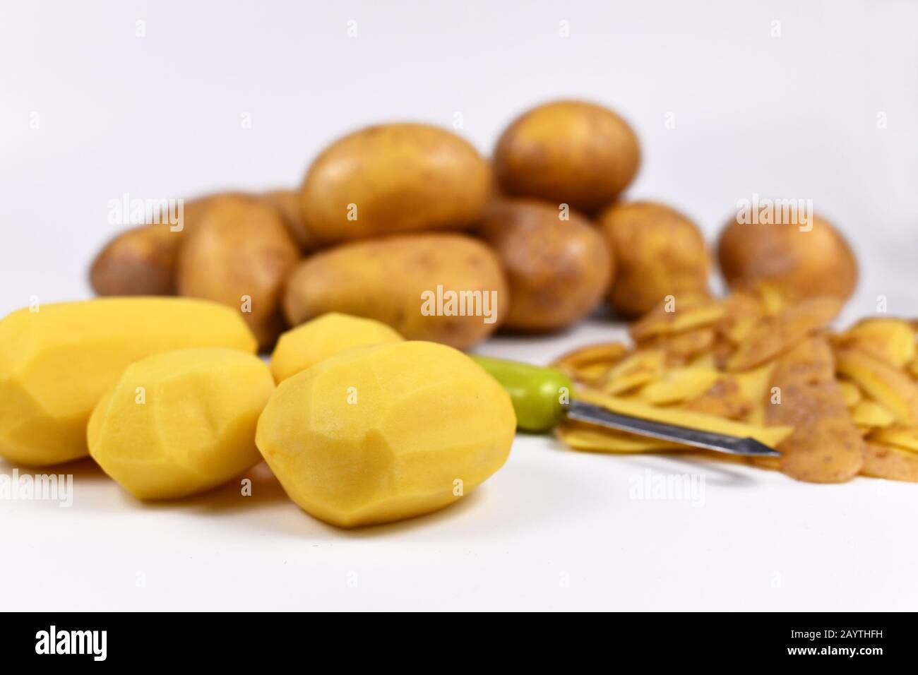 Préparation de la nourriture avec potatos pelés, peels et pommes de terre entières en arrière-plan Banque D'Images
