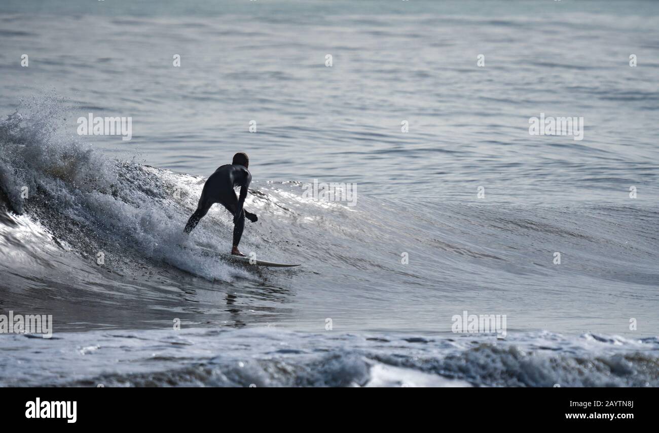 Vue arrière de la silhouette d'un surfeur isolé sur la vague Banque D'Images