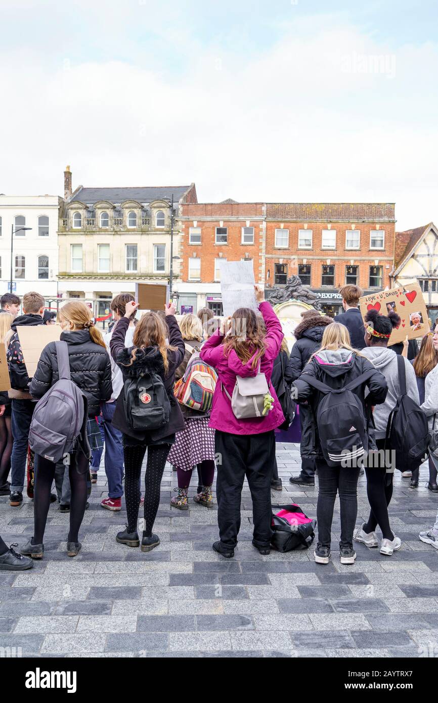 Vue d'un groupe de filles d'école de derrière avec des sacs à dos sur leur dos tenant des pancartes à une grève de jeunes pour la manifestation sur le changement climatique Banque D'Images