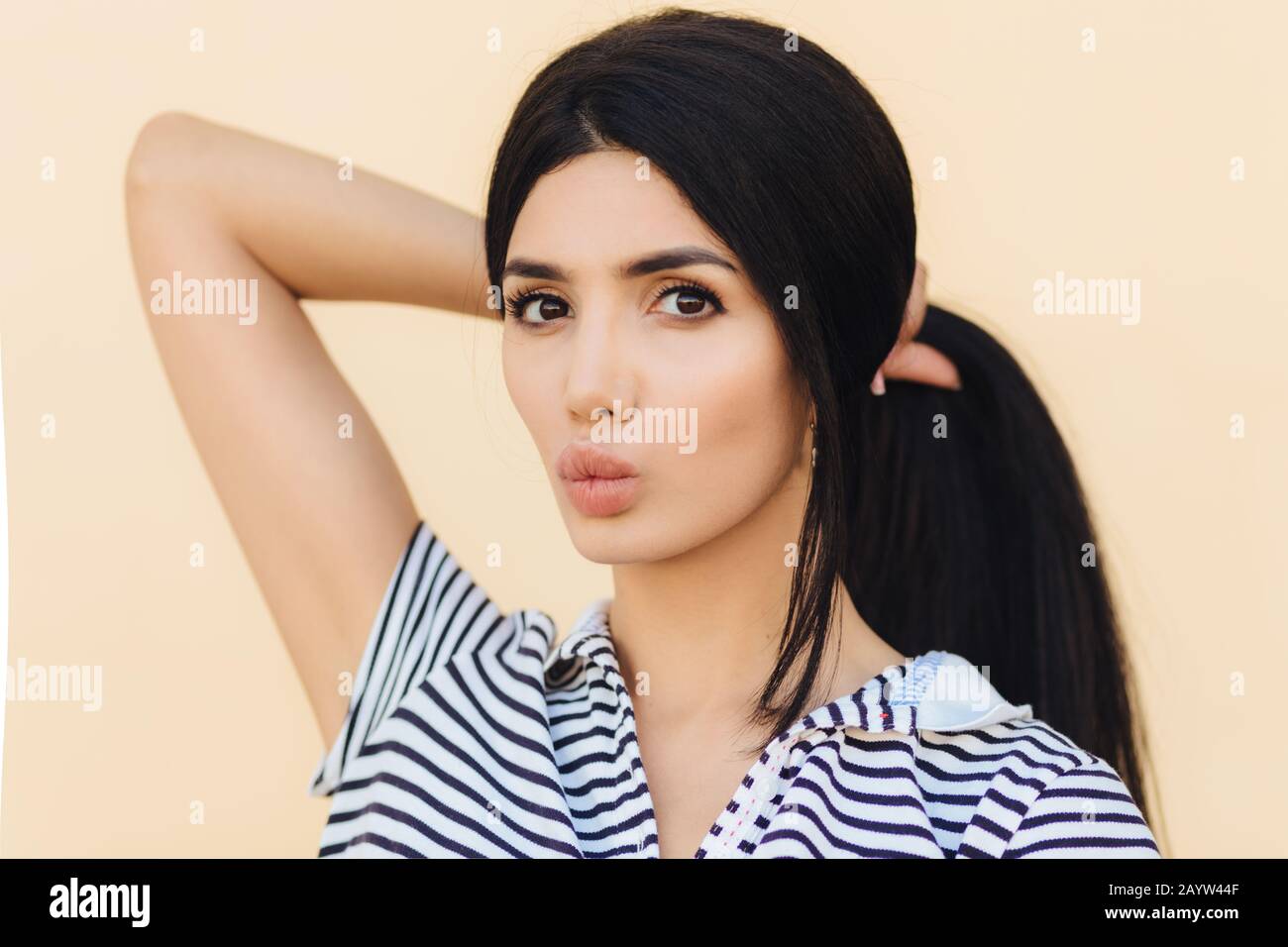 Jolie femme avec des cheveux sombres, maquillage, lèvres de couts, queue de poney, a une peau saine, vêtu de vêtements décontractés, isolé sur fond clair. Personne Banque D'Images