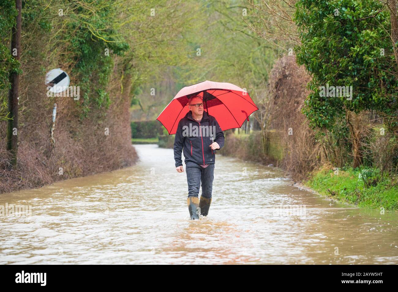 L'homme descend une route inondée tenant un parapluie, pendant la tempête Dennis. Beaucoup Hadham, Hertfordshire. ROYAUME-UNI Banque D'Images