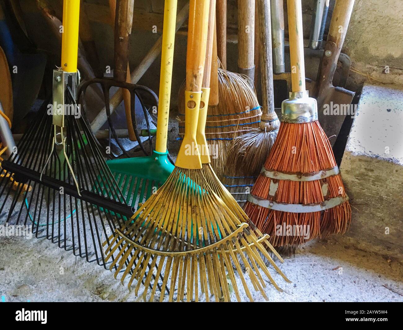 Des râteaux, des balais, des spades et des pelles colorés sont prêts sur le terrain pour le jardinage Banque D'Images