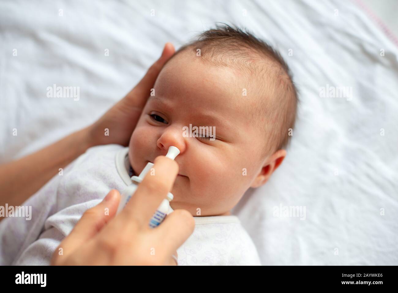 Femme à l'aide de spray nasal pour bébé Banque D'Images