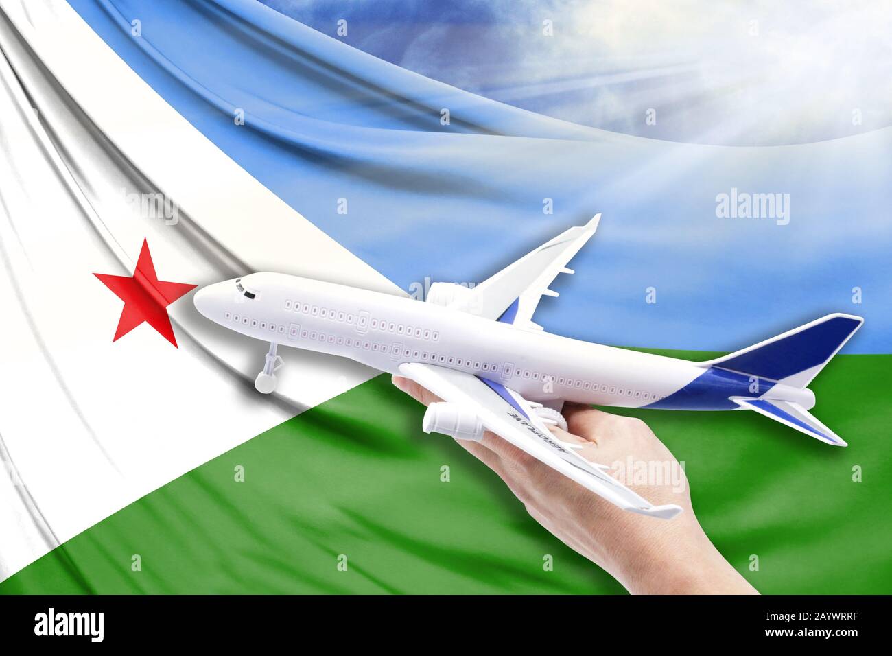 Avion en main avec le drapeau national de Djibouti sur un fond de ciel bleu avec des rayons de soleil Banque D'Images