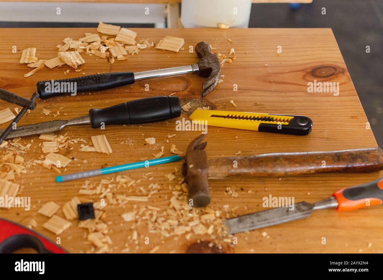 Marteaux, burin, cutter, crayon maintenu sur une table désordonnée remplie de copeaux de bois de déchets. Certains outils utilisés dans l'atelier de travail du bois. Banque D'Images