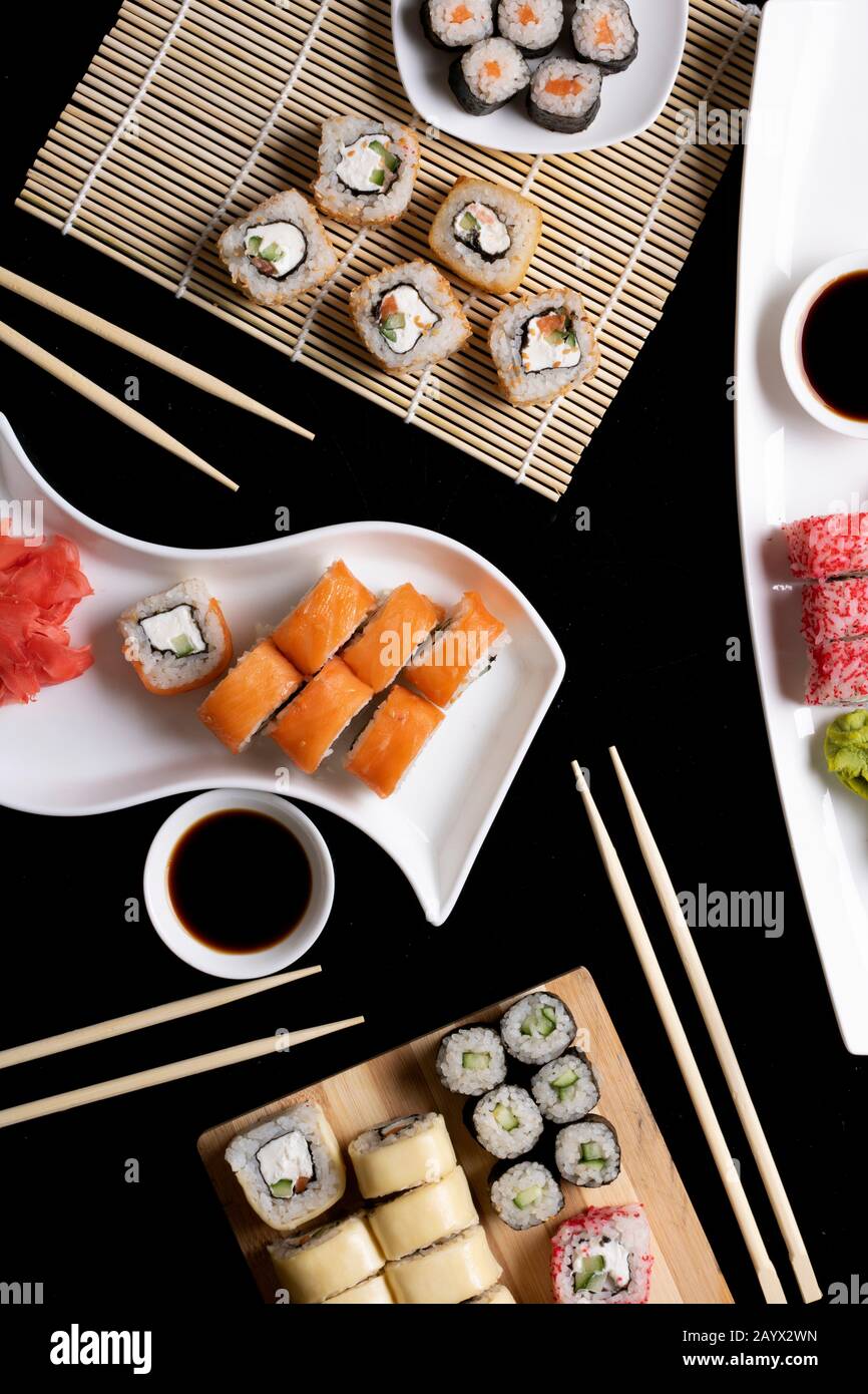 Sushi avec baguettes. Les sushis roulent la cuisine japonaise au restaurant. Jeu de rouleaux de sushi de Californie avec saumon, légumes. Image verticale Banque D'Images