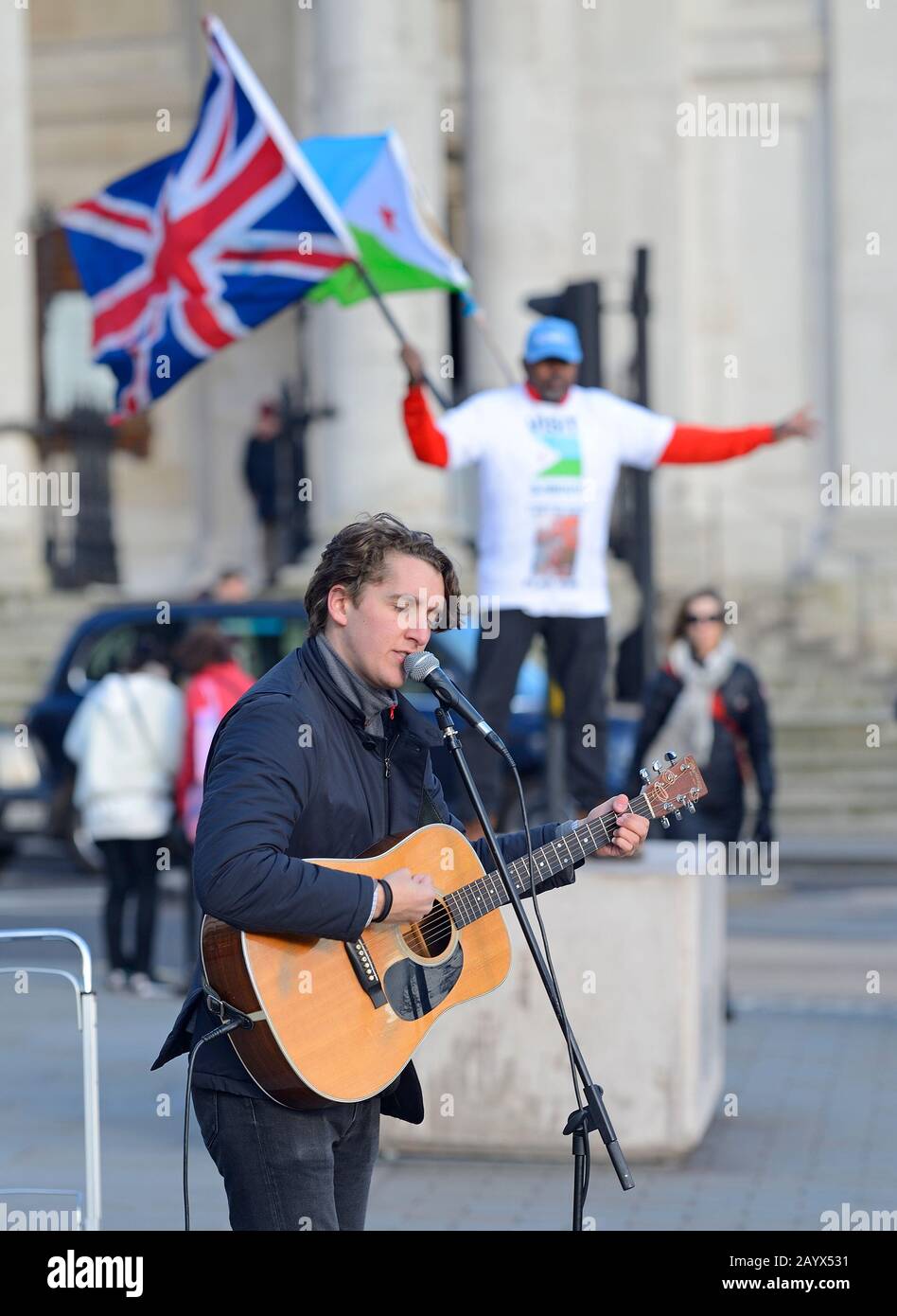 Londres, Angleterre, Royaume-Uni. Bustier chantant sur Trafalgar Square avec un homme qui agitant des drapeaux lui behing Banque D'Images