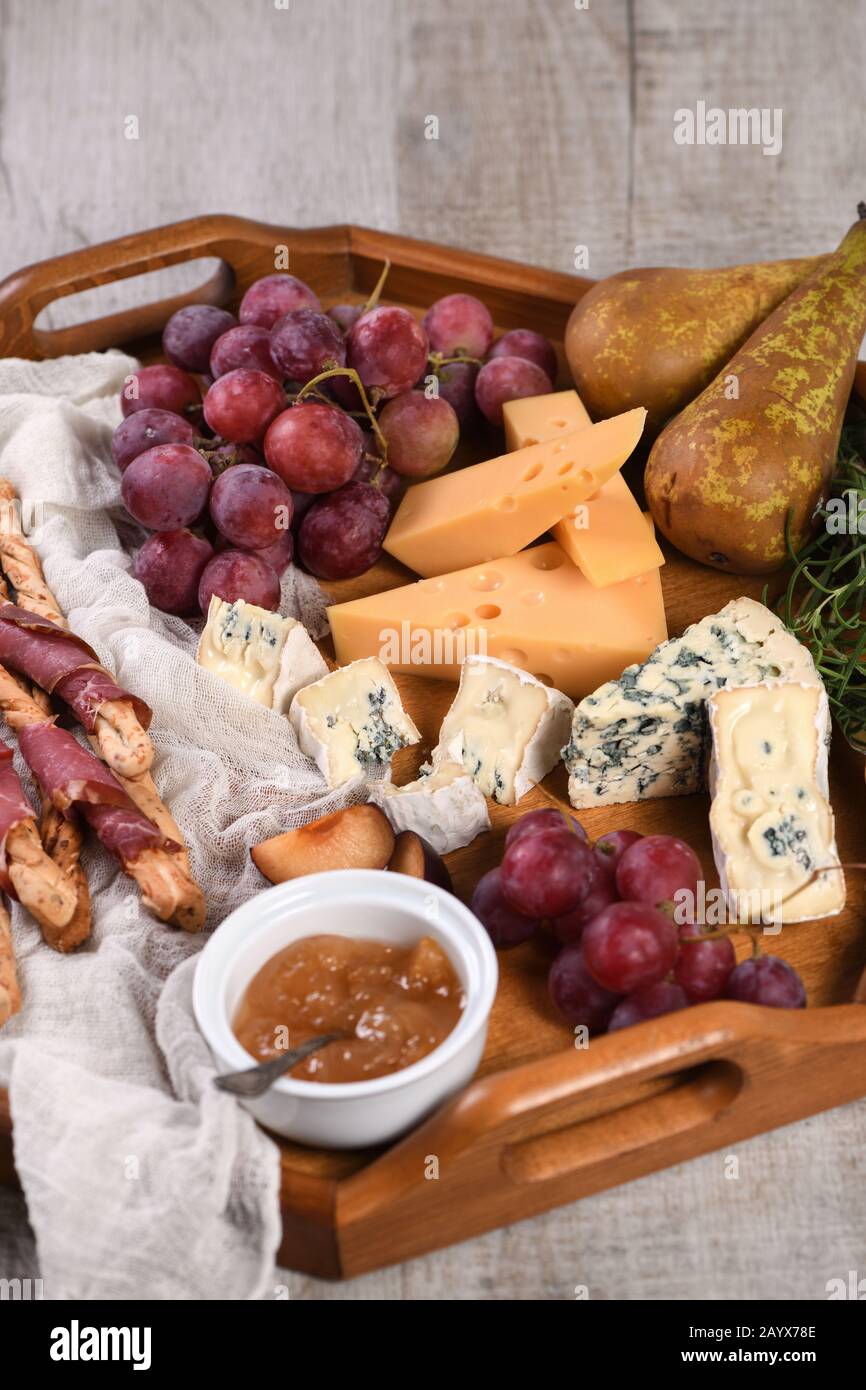 Antipasto. Plat avec du gruissini croustillant enveloppé de bacon séché, tranches de fromage brie, camembert, fromage bleu et raisin de muscat avec fruits Banque D'Images