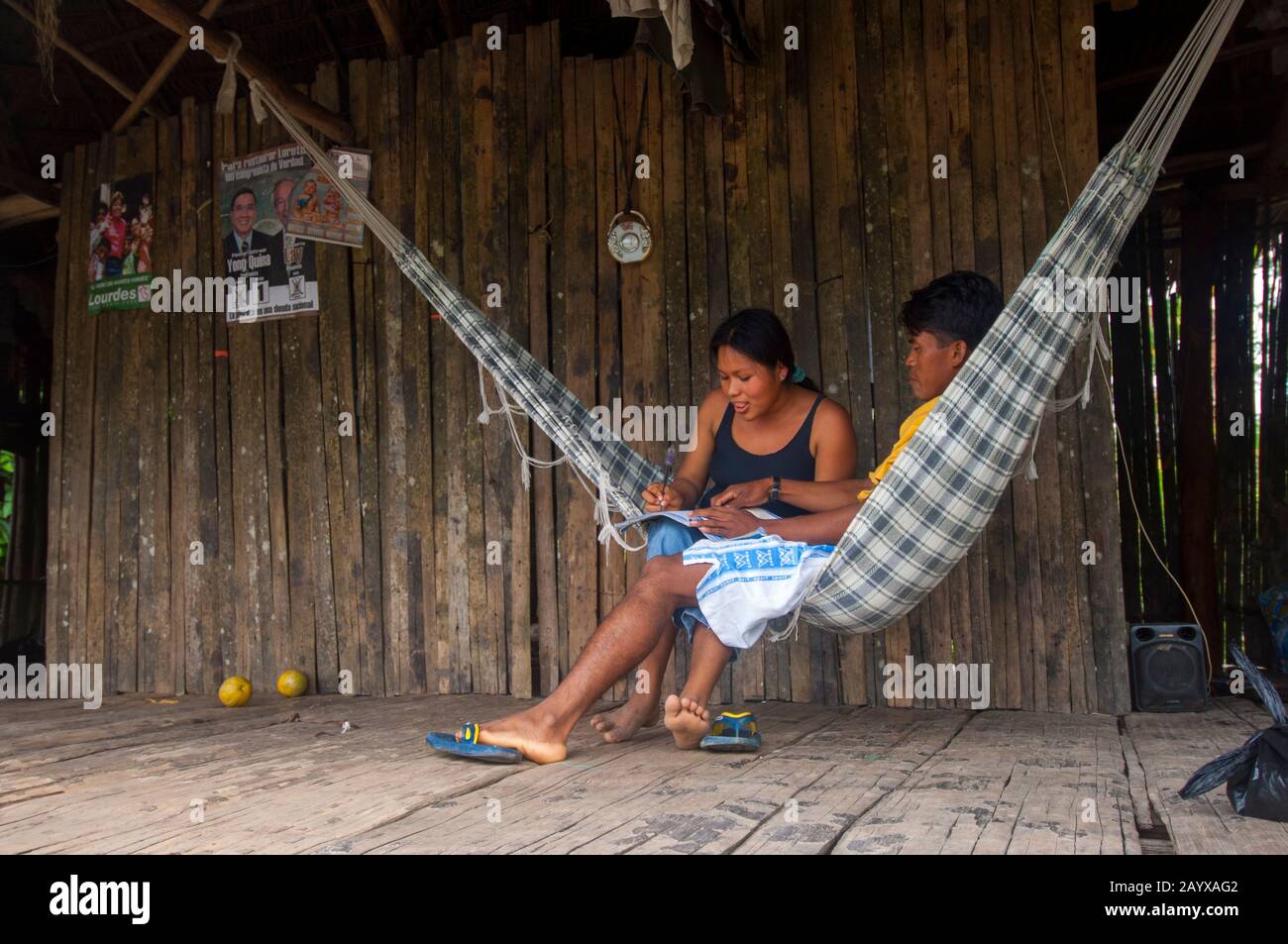 Un couple dans un hamac dans une maison sur pilotis dans un village le long de la rivière Maranon dans le bassin de la rivière Amazone péruvienne près d'Iquitos. Banque D'Images