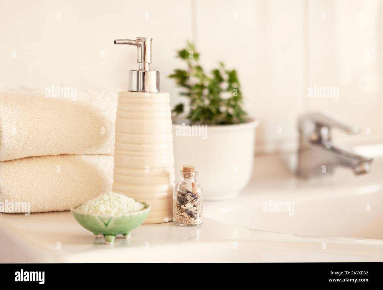 Savon céramique, bouteille de shampooing, bol avec sel de bain et serviettes en coton blanc sur fond De salle De bains Flou avec évier et robinet. Banque D'Images