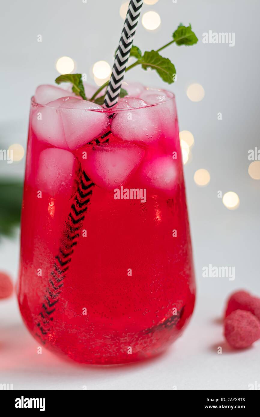 Boisson aux framboises et aux baies dans un verre transparent avec de la glace. Ajout de branches de palmiers et de framboises. Fond blanc. Espace de copie Banque D'Images