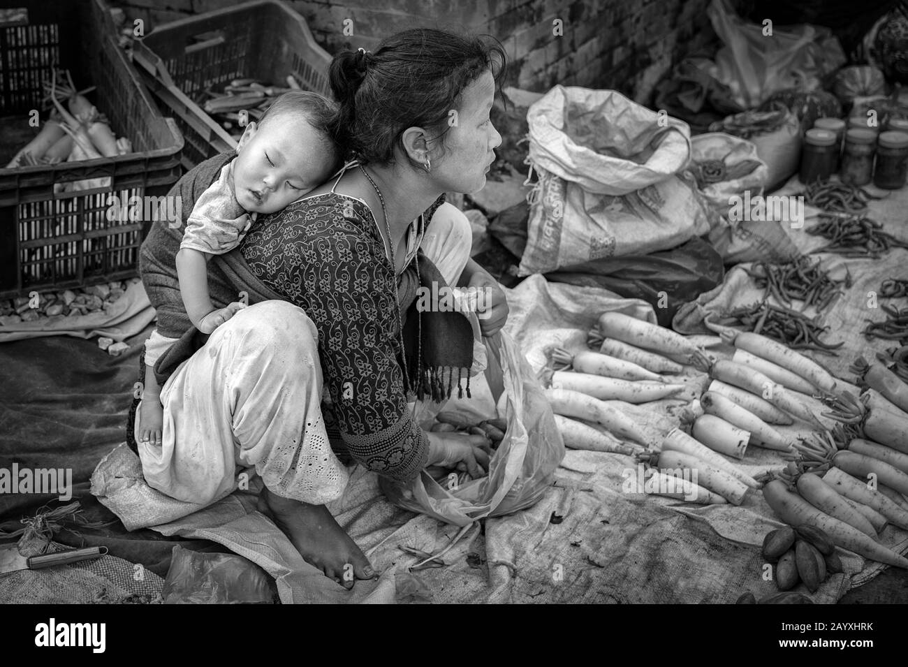 Une femme népalaise non identifiée avec un petit enfant vendant des légumes à Bhaktapur, classée au patrimoine mondial par l'UNESCO pour sa riche culture, les temples Banque D'Images