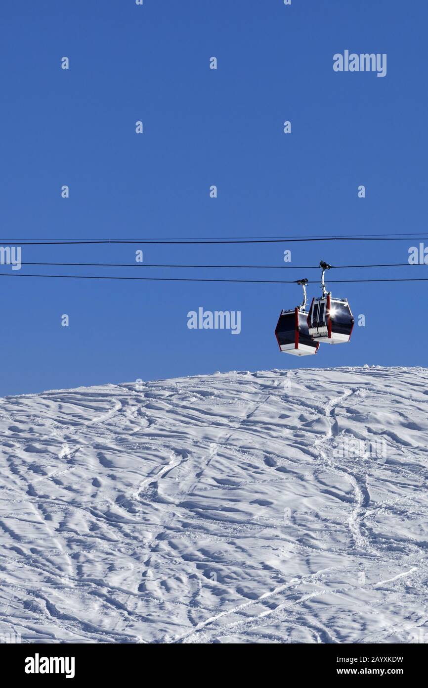 Télécabine, piste de ski hors piste avec trace de skis et de snowboards. Haute montagne d'hiver et ciel bleu clair en journée ensoleillée. Banque D'Images