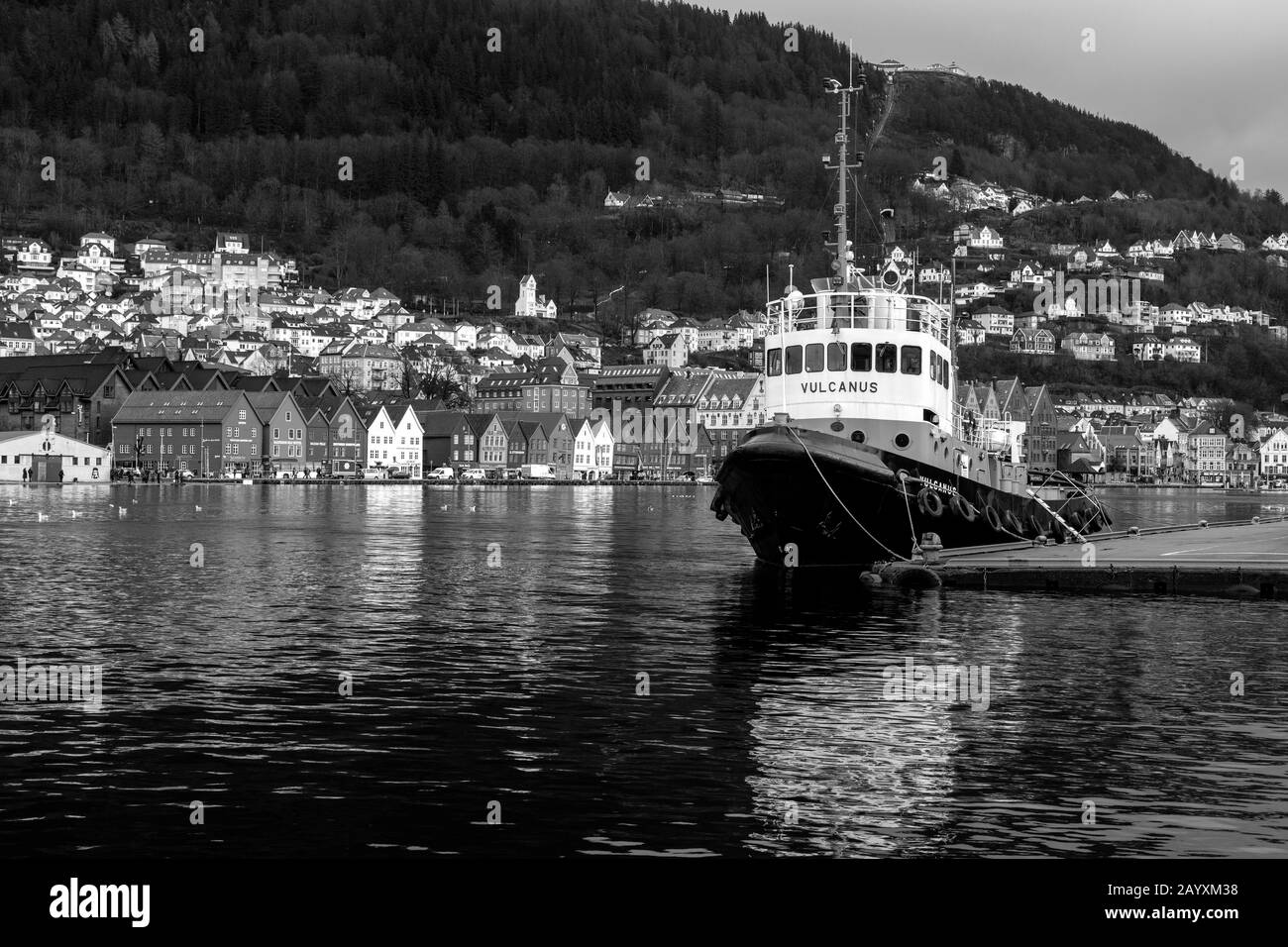 Vétéran tug bateau Vulcanus amarré à Port de Bergen, Norvège. Eau haute exceptionnelle, ondes de tempête. Bryggen et Mount Floyen en arrière-plan. Banque D'Images