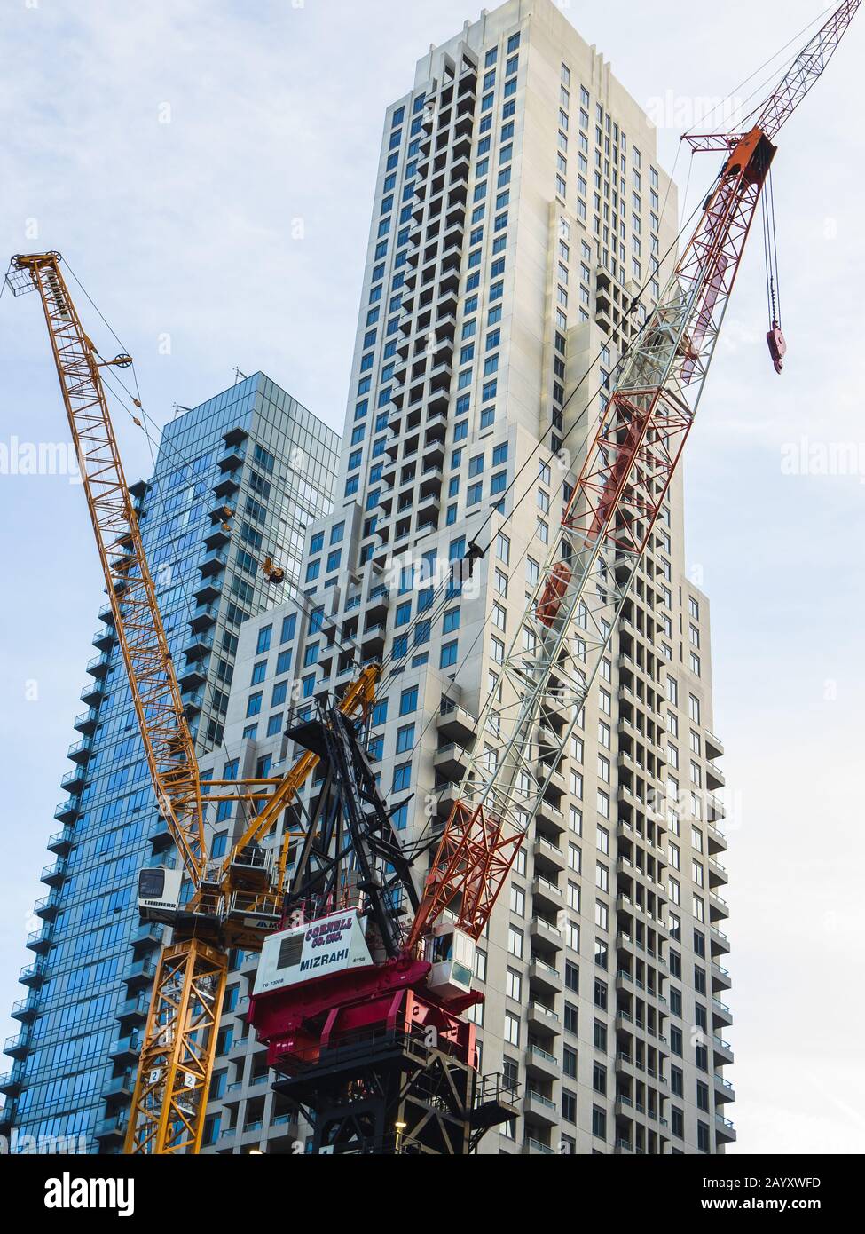 Grues de construction travaillant au centre-ville de Toronto avec un gratte-ciel en verre et un autre gratte-ciel derrière lui, sur Yonge et Bloor. Banque D'Images