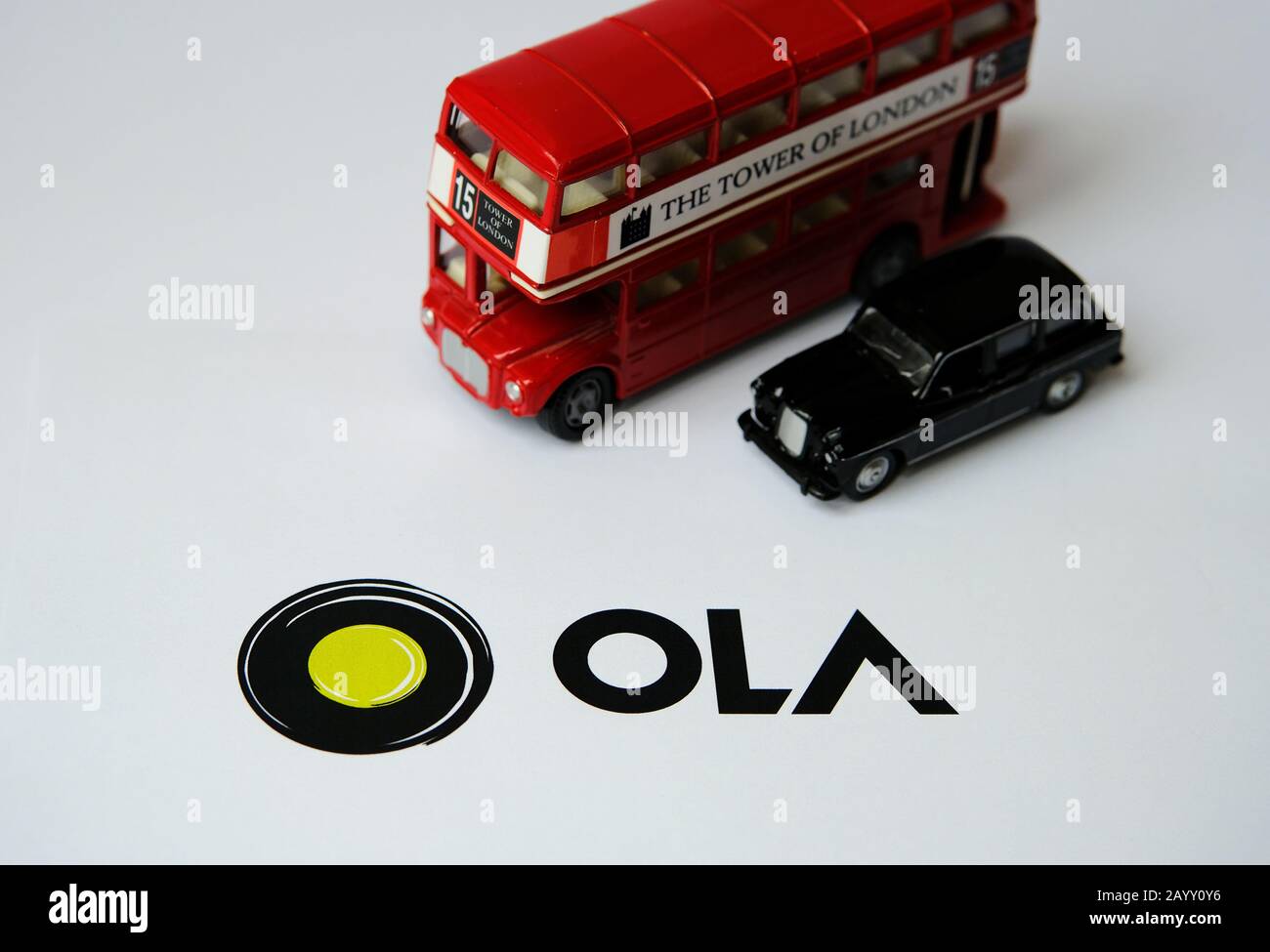 Logo OLA CAS APP sur brochure papier et cabine avec bus à double pont sur fond flou. OLA Cabs est une société de partage de parcours. Mise au point sélective. Banque D'Images