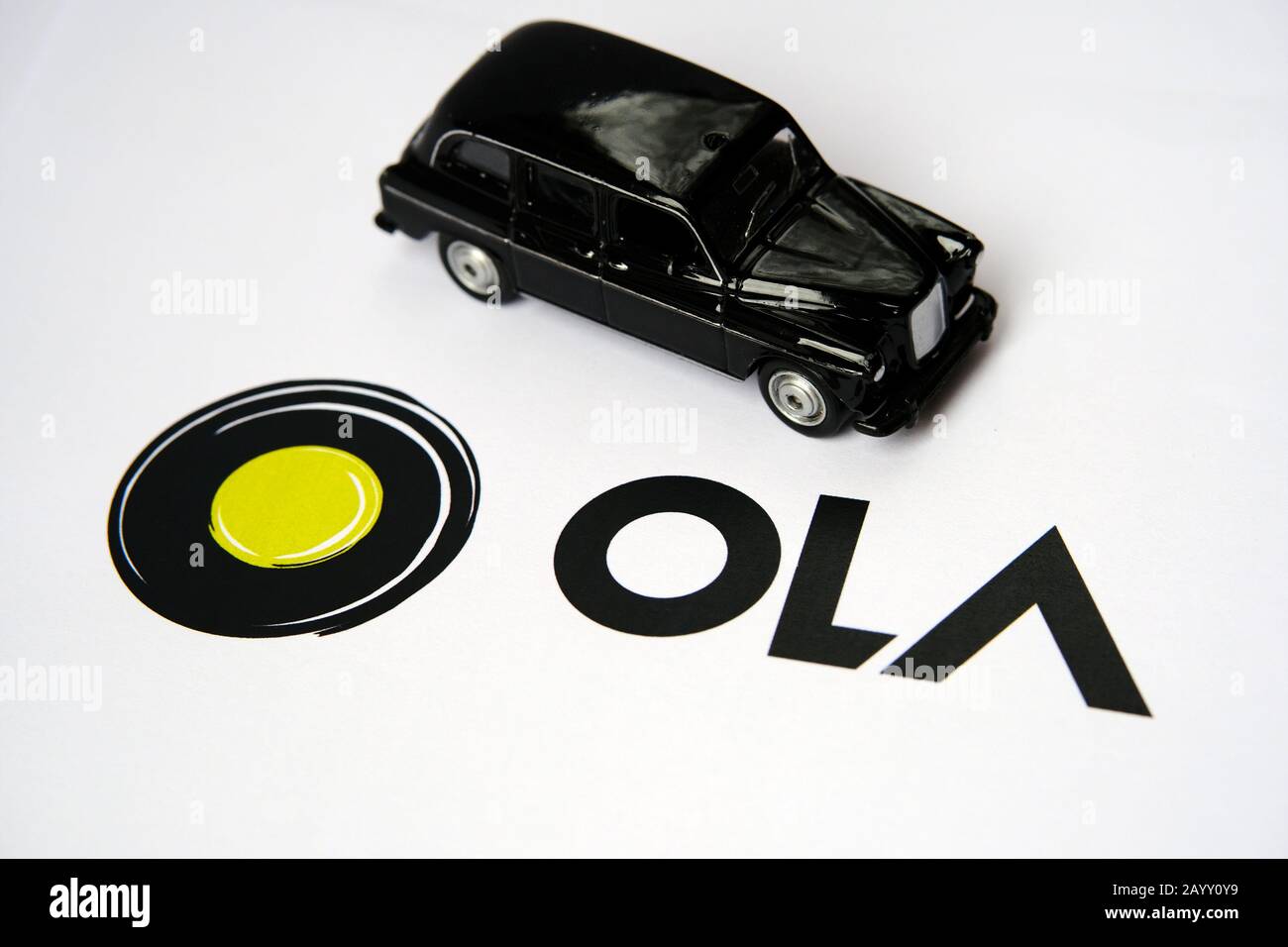 Logo OLA APP sur brochure papier et cabine noire sur fond flou. OLA Cabs est une société de partage de parcours. Mise au point sélective. Banque D'Images