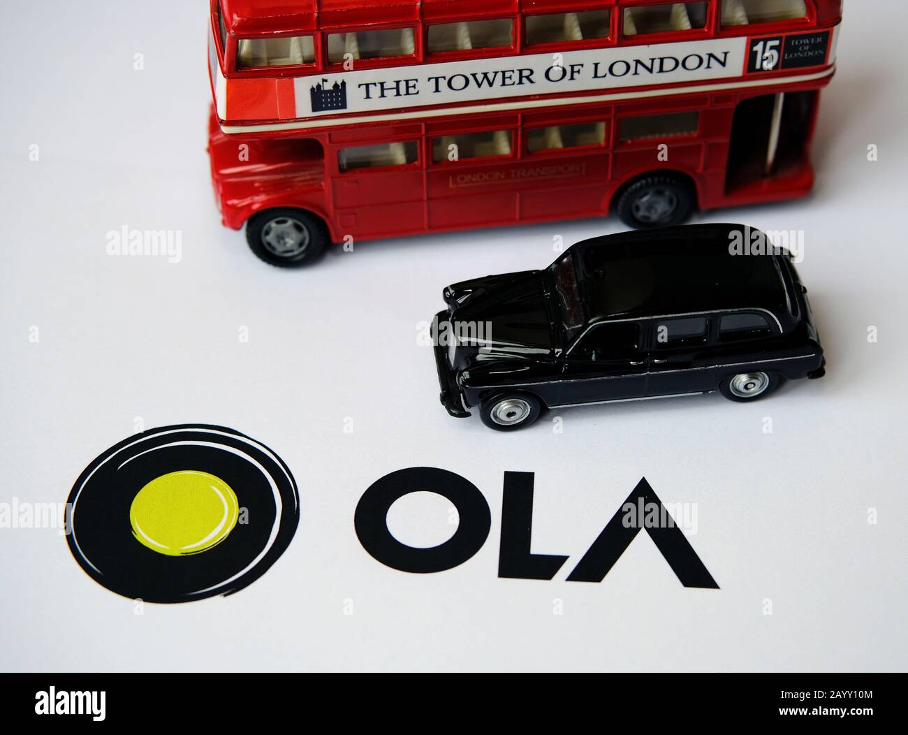 Logo OLA CAS APP sur brochure papier et cabine avec bus à double pont sur fond flou. OLA Cabs est une société de partage de parcours. Mise au point sélective. Banque D'Images