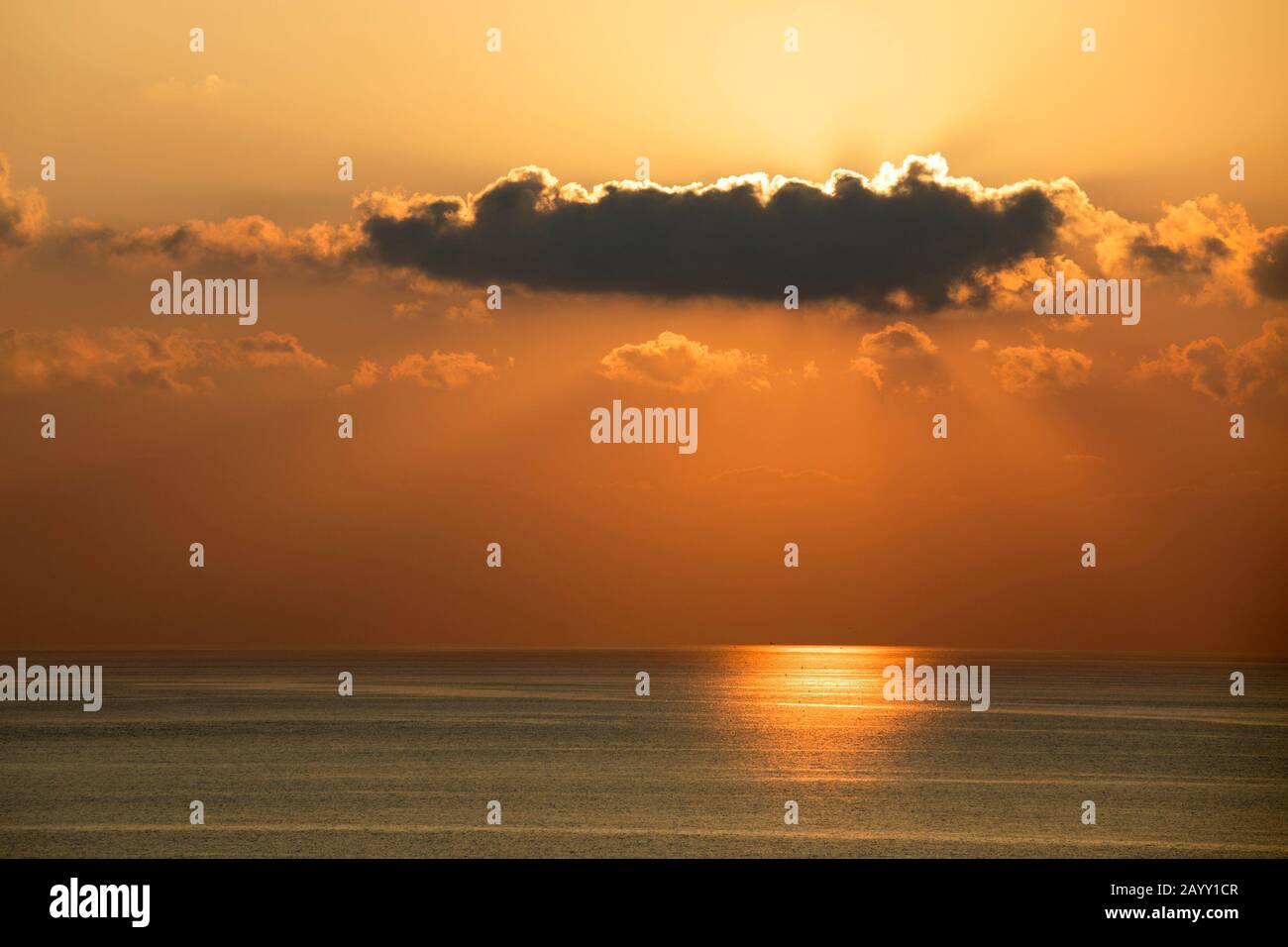 Nuage foncé bloquant le soleil couchant dans le ciel orange du soir au-dessus de la mer Méditerranée Banque D'Images