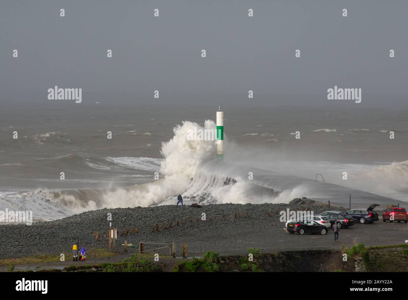 Le temps de tempête crée de grandes vagues qui frappent dans Aberystwyth, au Pays de Galles, tandis que les spectateurs sont éclipis par la taille des vagues. Banque D'Images