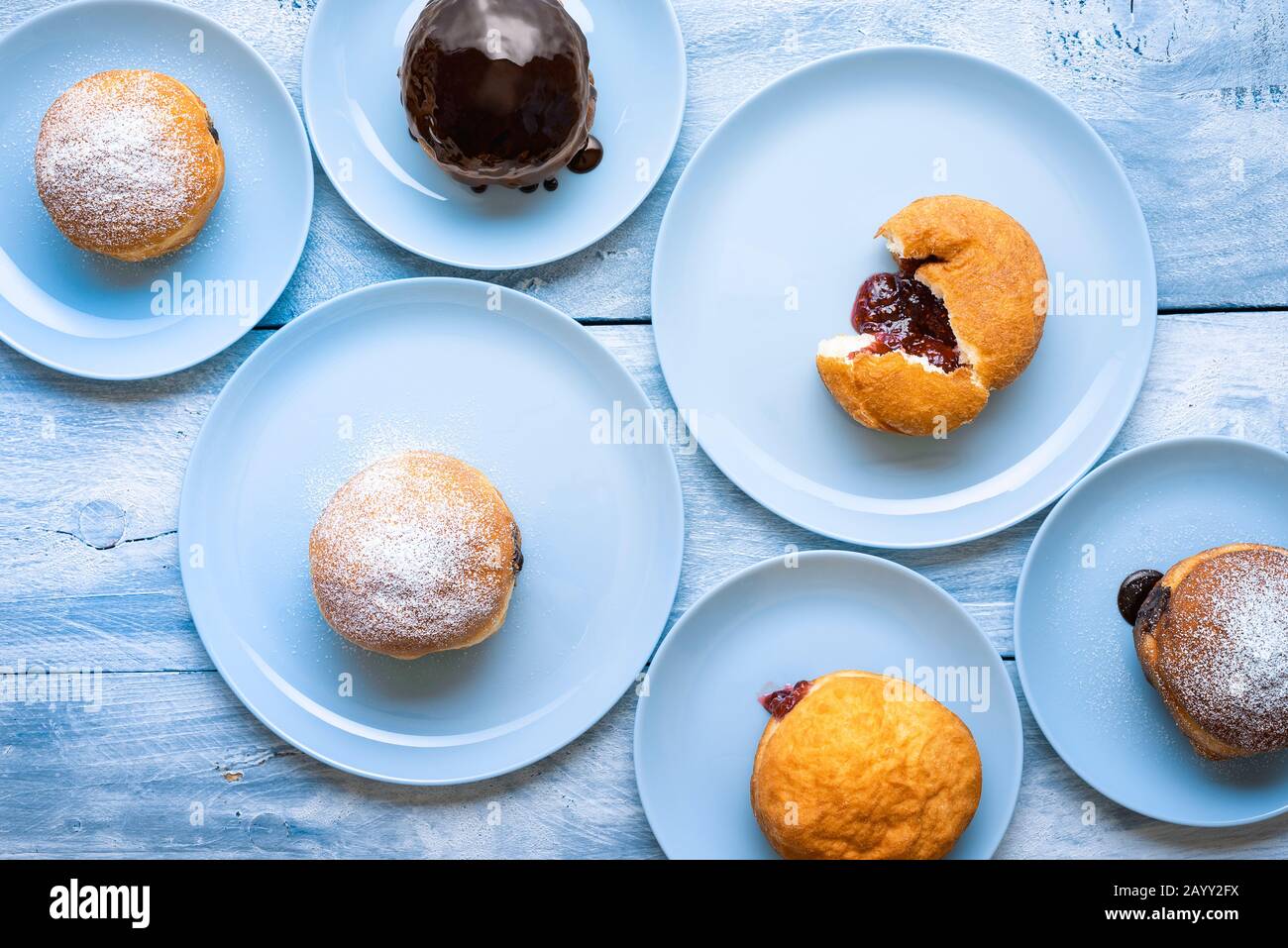 Beignets remplis de confiture et de chocolat sur des plaques bleues sur une table en bois. Vue sur les beignets berliner. Beignets faits maison. Beignets Berliner. Banque D'Images