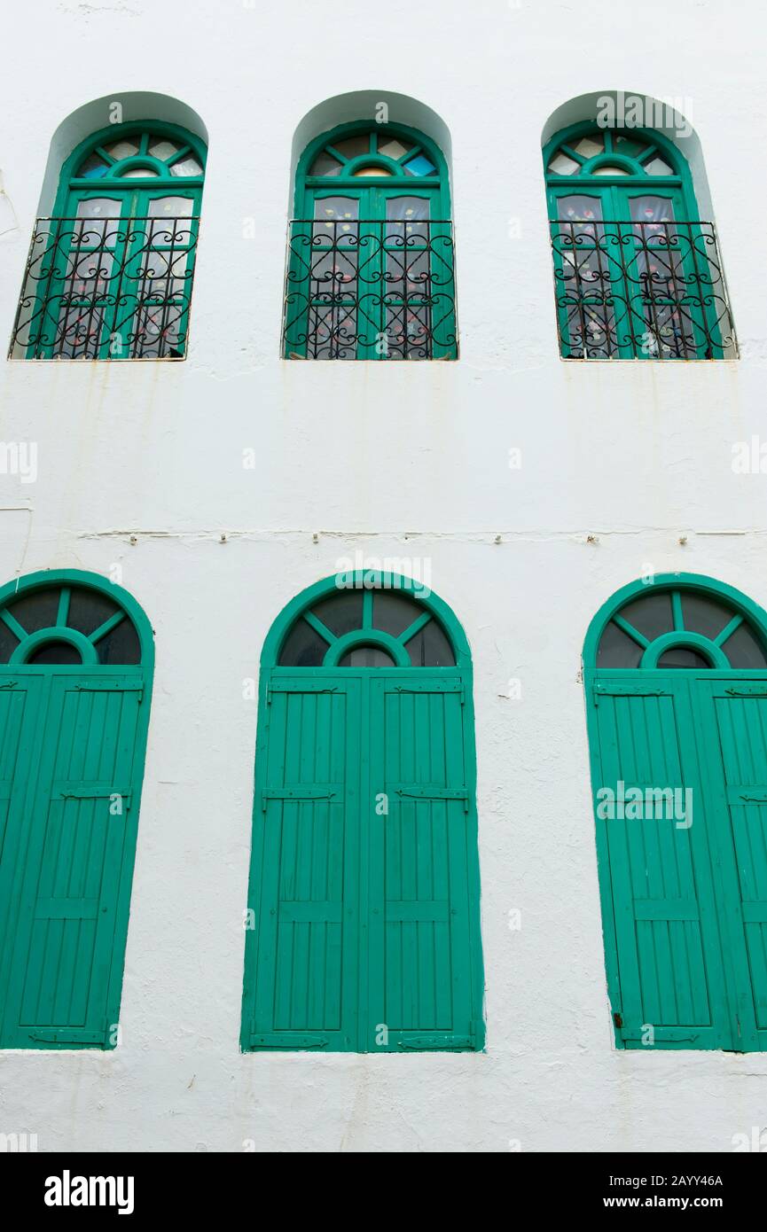 Scène de rue avec des fenêtres vertes dans la petite ville d'Asilah près de Tanger, Maroc. Banque D'Images