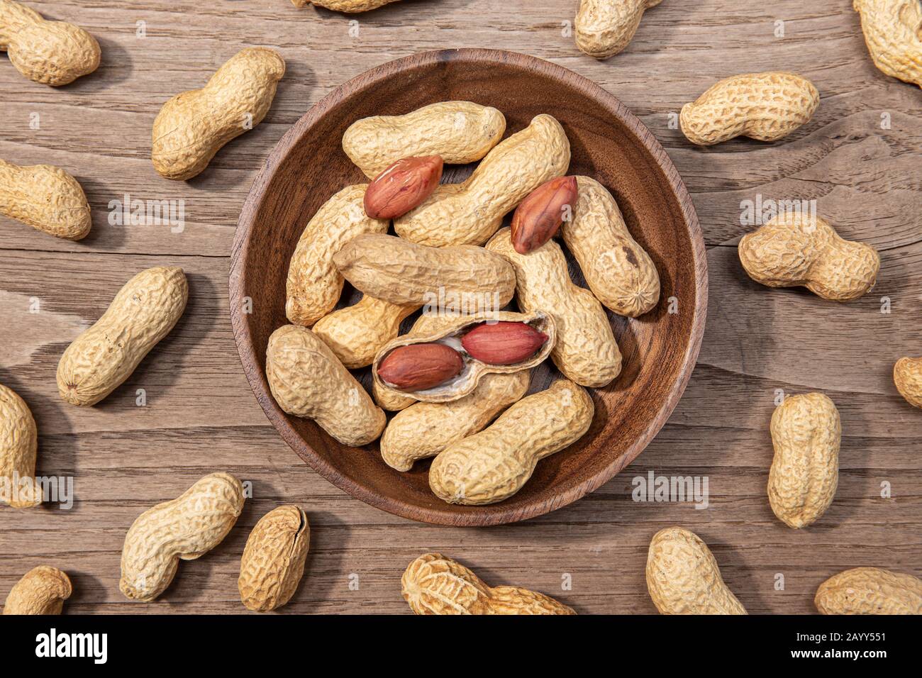 Arachides dans un bol sur une table en bois rustique. Arachis hypogaea Banque D'Images