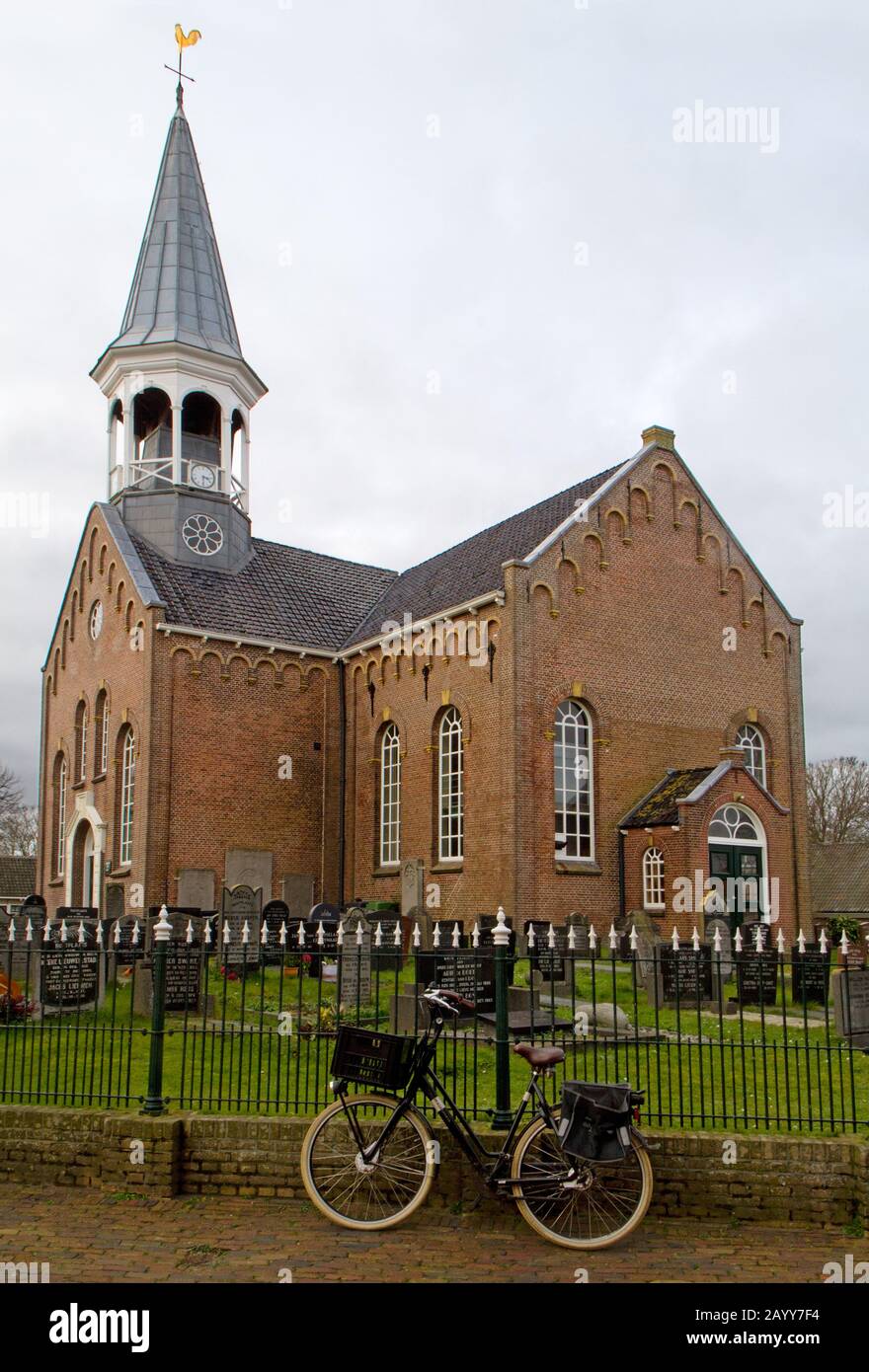 Église de Midsland sur l'île de Terschelling aux Pays-Bas, entourée d'une clôture en fer forgé, une bicyclette garée contre elle Banque D'Images