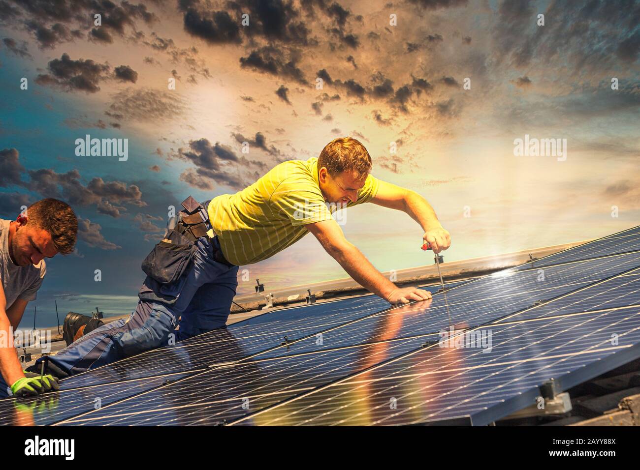 Portrait des travailleurs qui installent des panneaux photovoltaïques sur le toit Banque D'Images