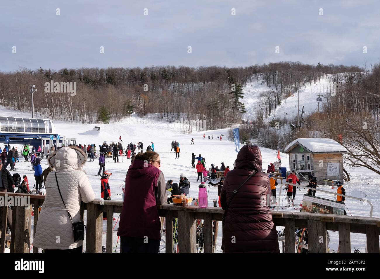 Les gens sur la véranda du chalet qui regardent sur la foule en ski de Camp Fortune, Chelsea, Québec, Canada. Banque D'Images