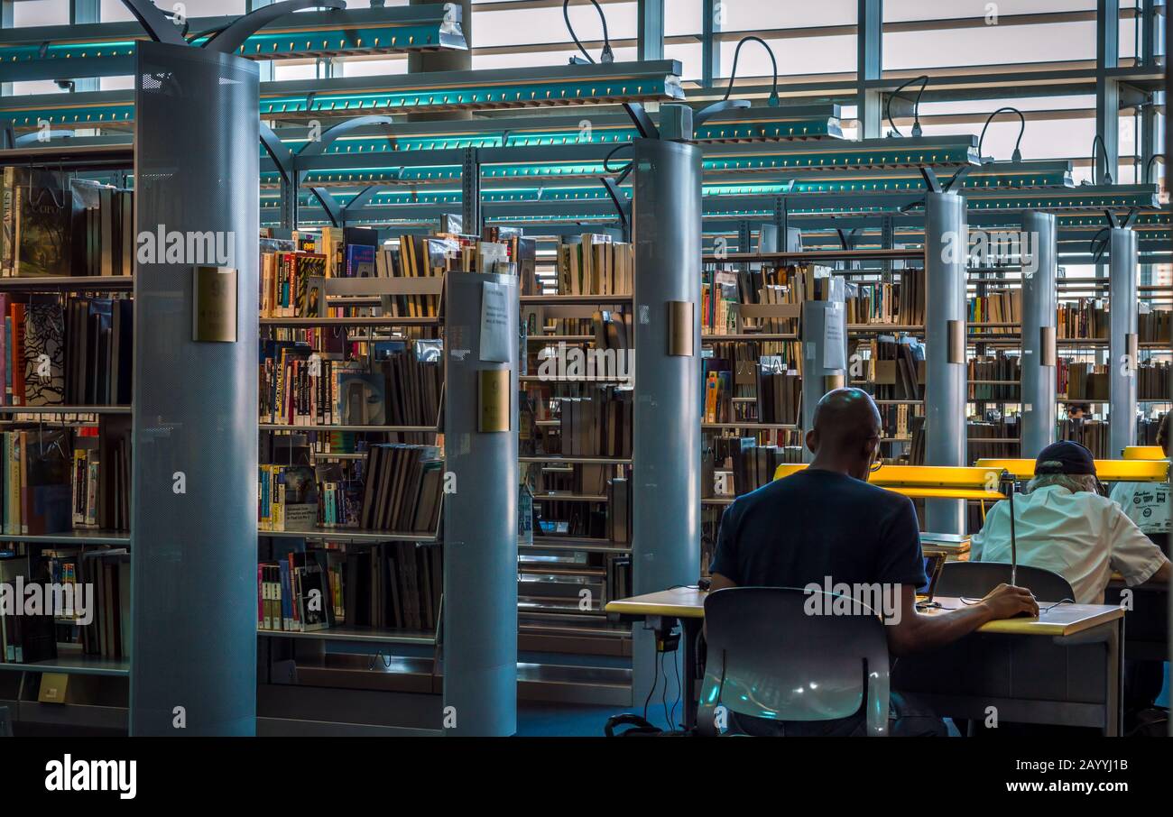 Dos d'hommes assis sur un bureau regardant leurs ordinateurs portables à la bibliothèque centrale Burton Barr dans le centre-ville de Phoenix, Arizona. Banque D'Images