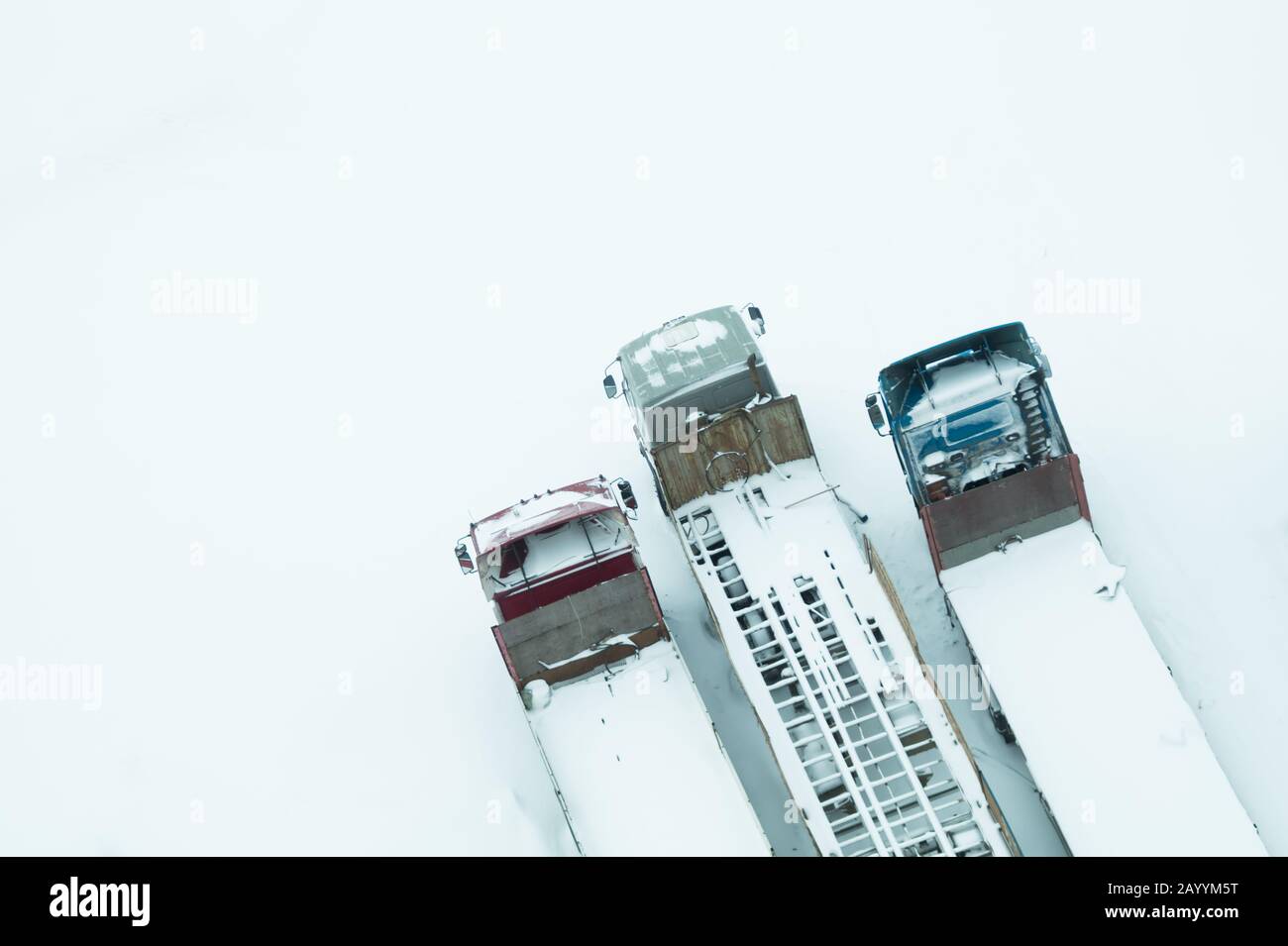 Camion sous la neige. Camion recouvert de neige après la neige. Camions longs se tiennent dans une vue de dessus de rangée. Concept de transport. Véhicules enneigés. AERI Banque D'Images