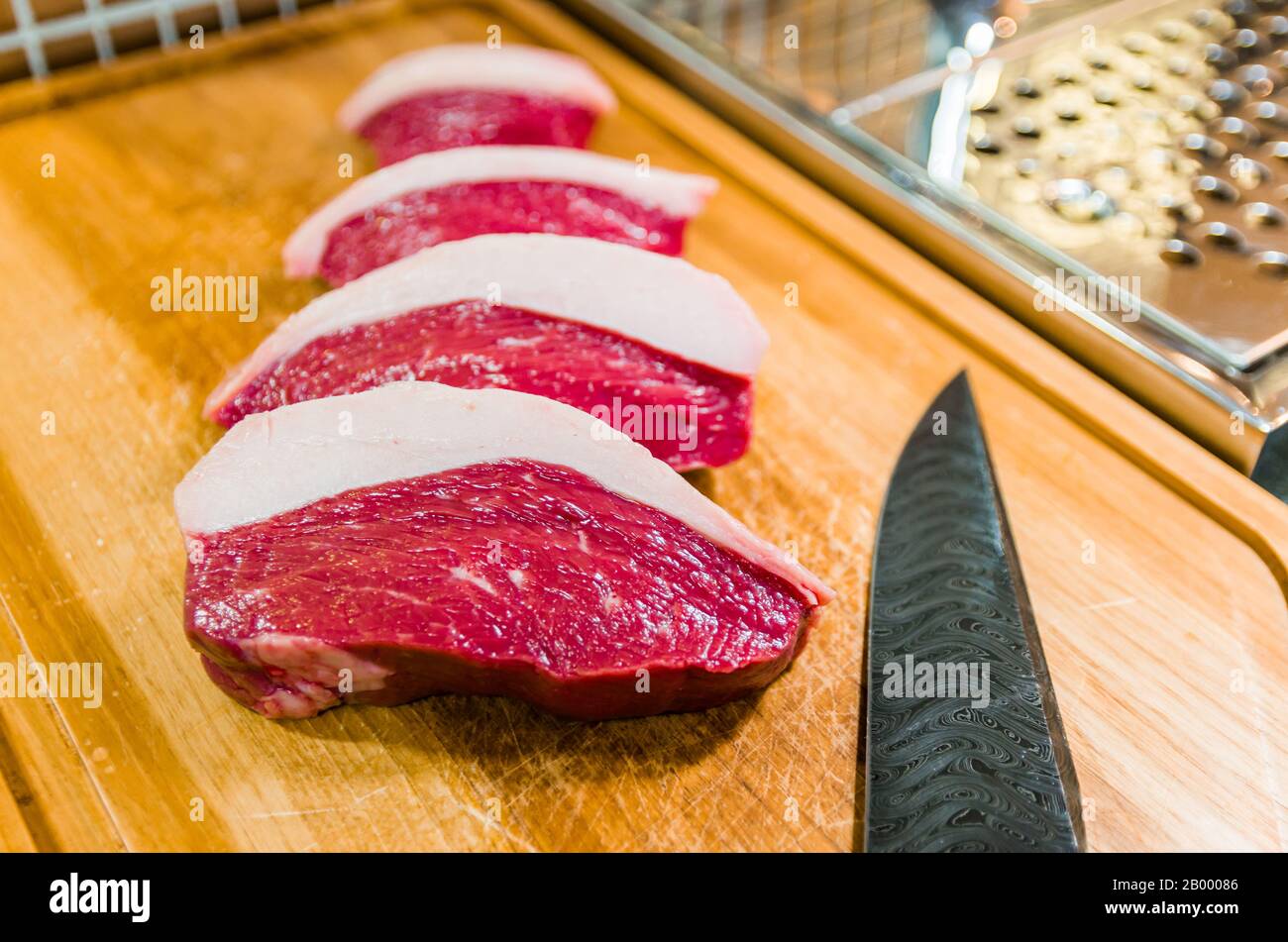 Belle photo de Picanha (top sirloin CAP) coupe sur une planche à découper en bois et un magnifique couteau en acier damassé personnalisé avec le motif brise arkasas. Banque D'Images