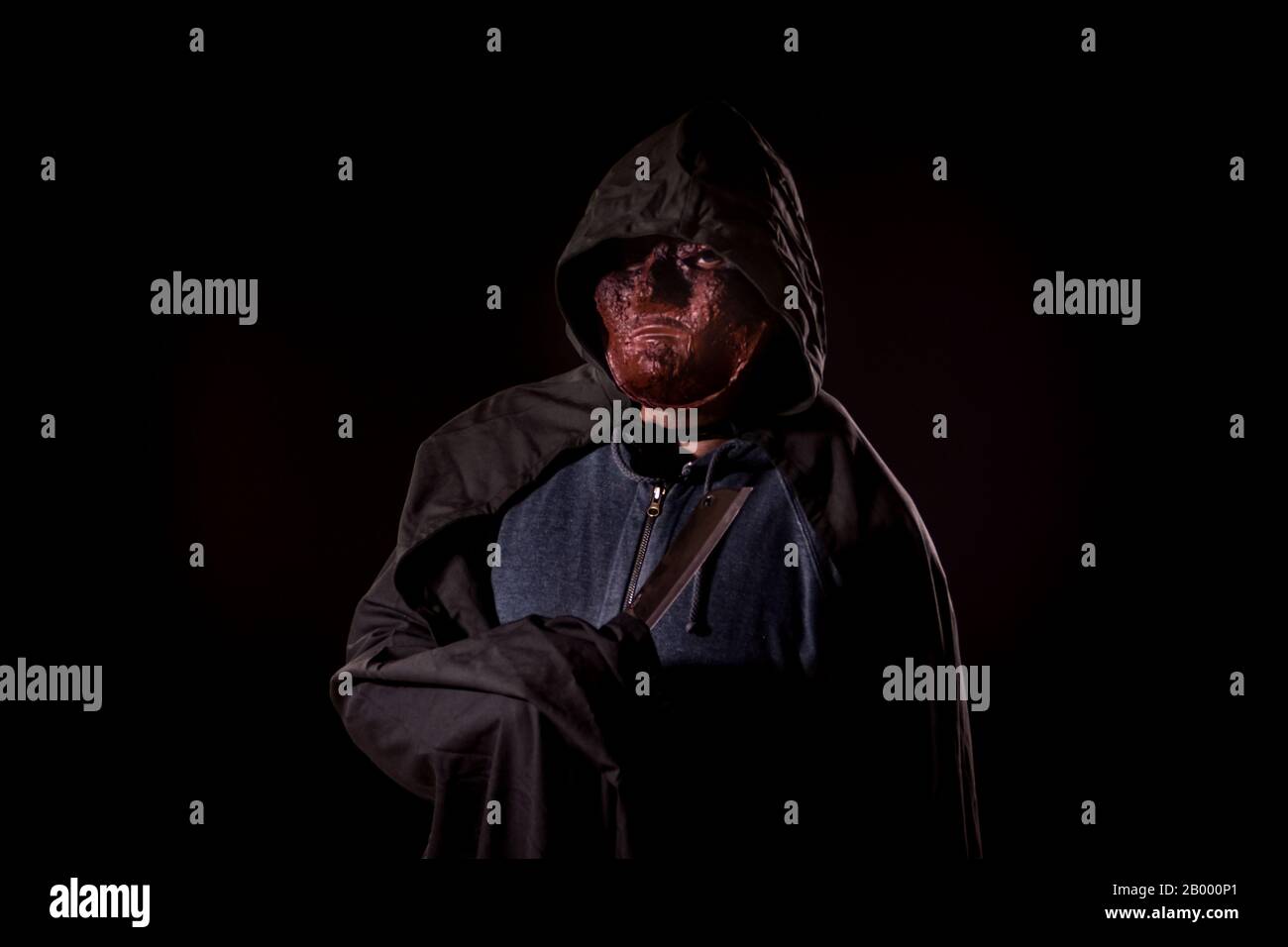 Tueur effrayant dans le masque et le couteau de maintien du sweat à capuche Banque D'Images