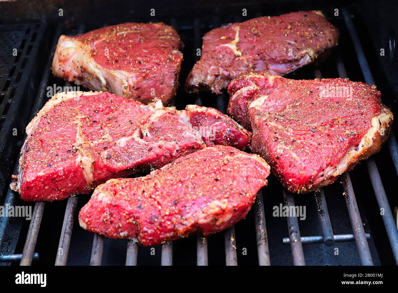 Steaks assaisonnés crus sur un barbecue. Banque D'Images