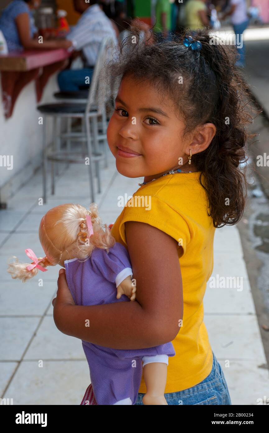 Portrait d'une fille tenant une poupée à la gare routière de la ville d'Upala au Costa Rica. Banque D'Images