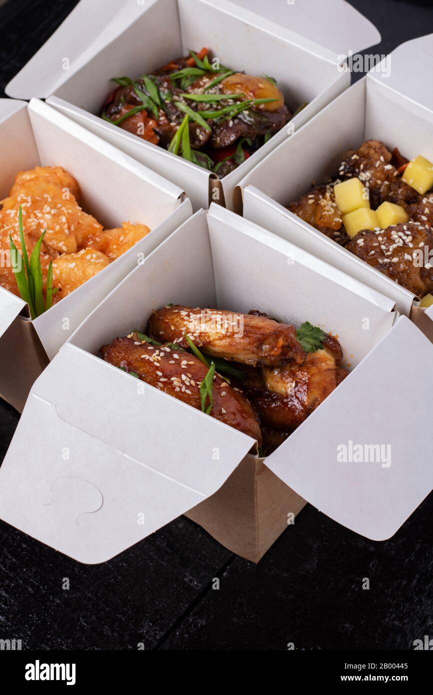 Assortiment de plats chinois dans des boîtes de livraison de papier :  poulet aigre et doux, nouilles, salade, riz, petits pains cuits à la  vapeur, sauces. Pose plate Photo Stock - Alamy