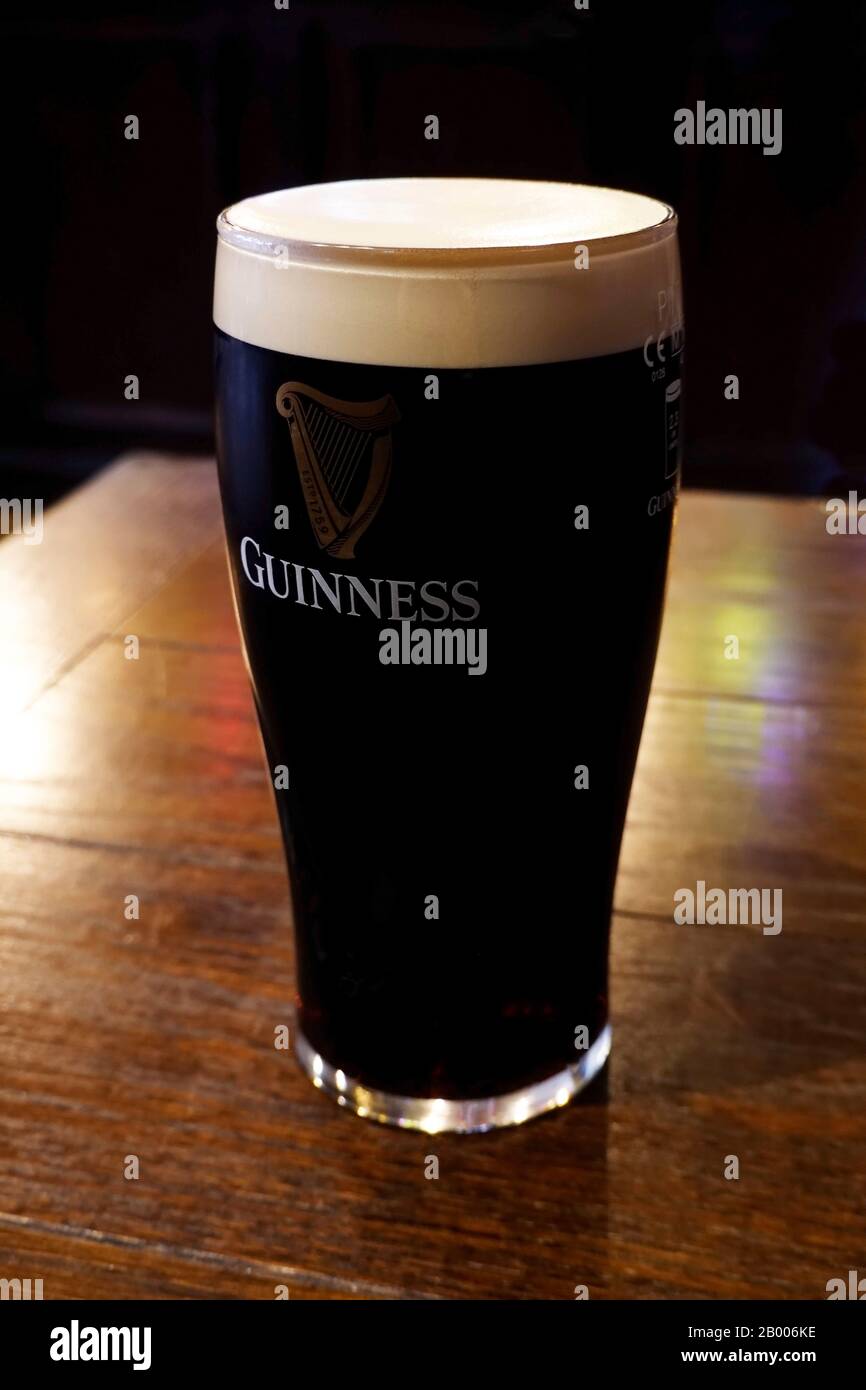 Une pinte de Guinness dans un grand verre de tulipe avec une tête de mousse parfaite Banque D'Images