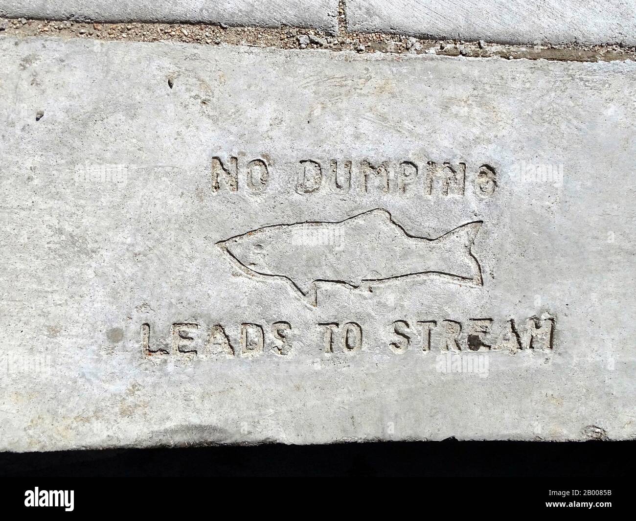 Un panneau de bordure de sentier par un drain indiquant « pas de dumping-Conduit au flux » Banque D'Images